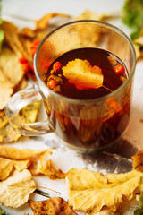 Autumn leaves and hot steaming cup of coffee. Wooden table on sun light background. Fall time concept.