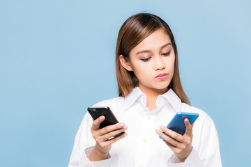 Young woman holding two smart phones.