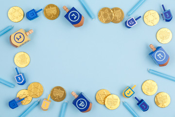 Blue background with multicolor dreidels, menora candles and chocolate coins. Hanukkah and judaic holiday concept. © Ekaterina_Molchanova