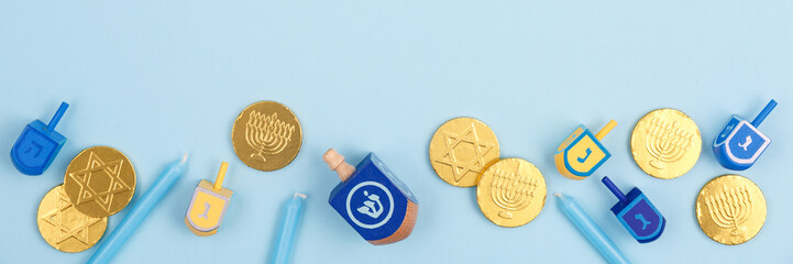Blue background with multicolor dreidels, menora candles and chocolate coins. Hanukkah and judaic...