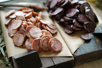 Caucasian organic raw sausage and ham on wooden stand and craft paper