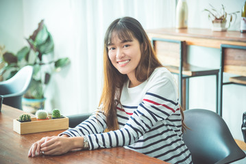 Beautiful young asian woman sitting at home and smiling at camera