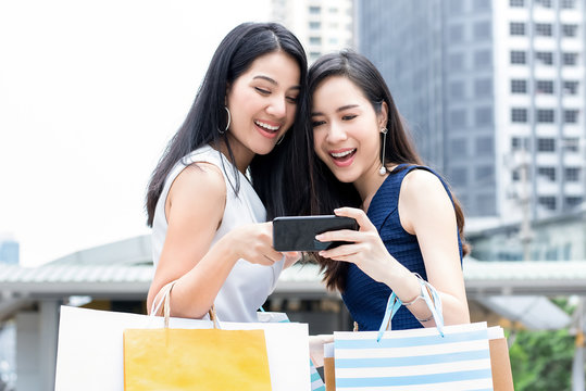 Asian Women Enjoy Shopping Online Via Smartphone While Travelling In The City