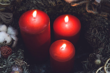 Red candles in a pine wreath with golden decorations and natural pinecones top view