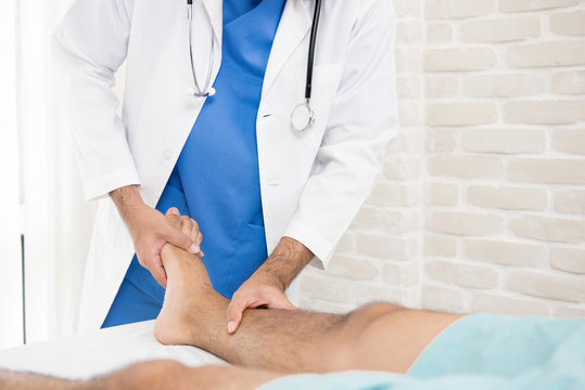 Doctor or physiotherapist giving treatment to broken leg patient