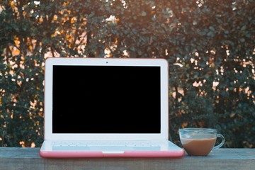 Laptop computer mock up in the garden and a cup of coffee. Modern digital lifestyle concept for digital marketing and social media.
