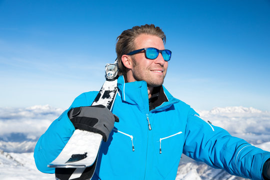 Young, sexy man is skiing in winter paradise in the alps with a beautiful blue sky and wonderful white snowy mountains 