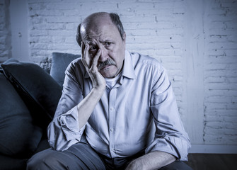 portrait of senior mature old man on his 60s at home couch alone feeling sad and worried suffering pain and depression