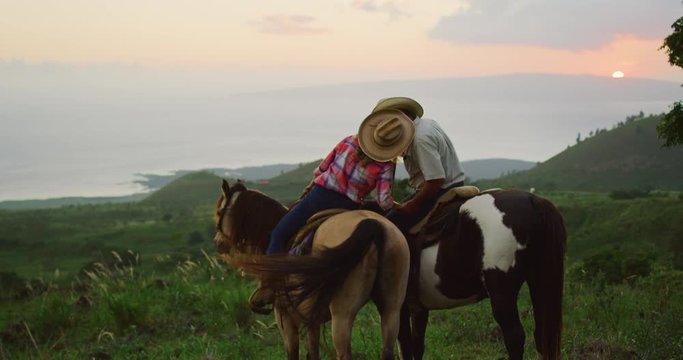 Couple horseback riding together at sunset