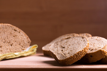 Jewish bread cut on pieces, slices on brown wooden background and fabric napkin