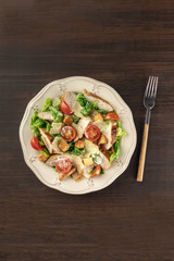 Chicken Caesar salad on dark rustic background with copyspace