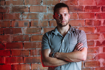 Young man wearing a check shirt against a brick wall.