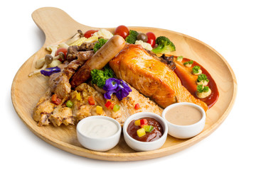Closeup grilled beef and salmon fish steak with sauces served in wood plate isolated on white background