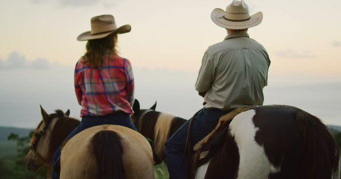 Couple horseback riding together at sunset