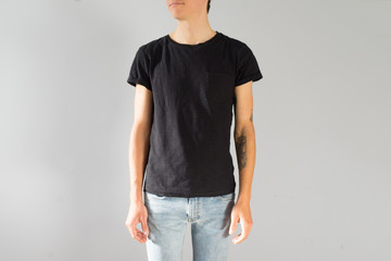 Front view on attractive and handsome young man with authentic hipster arm tattoos, in blue beanie, in black mockup simple tshirt from organic cotton, isolated on white background