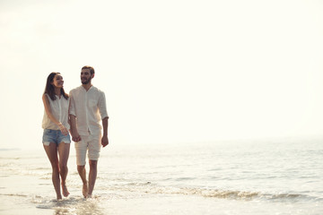 Happy fun beach vacations couple walking together laughing having fun on travel destination.