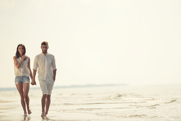 Happy fun beach vacations couple walking together laughing having fun on travel destination.