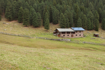 Rural scene from a refuge with photovoltaic panels among a mountain pasture in Val di Funes, Italy