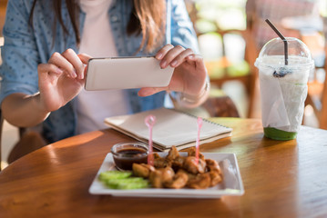 Hands of woman taking a photo of breakfast with smartphone..