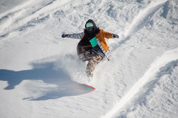 Snowboarder in colorful sportswear riding with snowboard down powder snow hill
