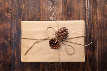 Christmas or New Year presents gift box with cones on a wooden natural warm white surface view from above. Closeup with clipping path