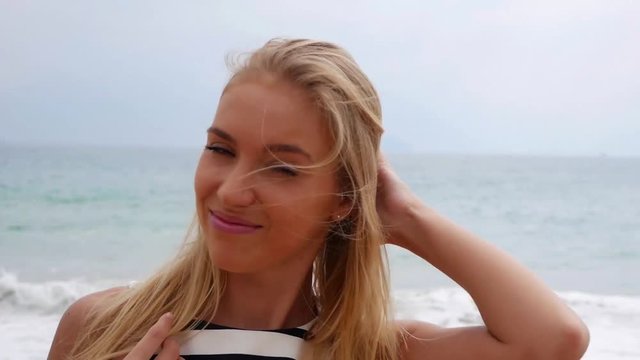 Closeup cheerful young beautiful girl smiling winking looking at camera over background at storm on the sea