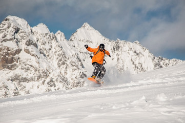 Naklejka na ściany i meble Active snowboarder riding on the mountain slope