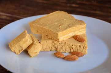 Spanish almond nougat in white plate on wooden table. Soft Turron the Jijona, traditional Christmas dessert in Spain. Christmas sweet background.