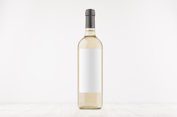 Transparent white wine bottle with blank white label on white wooden board, mock up. Template for...