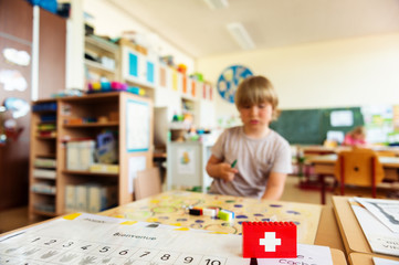 Background with cute little boy working in classroom, self made swiss flag, swiss primary education