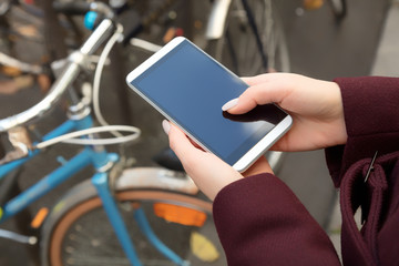 Girl holding cellphone in urban surroundings - shallow depth of field.