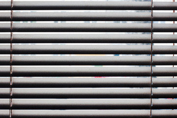 Fragment of the white Venetian blinds with lift cord and turning rod of a manual control on a foreground .