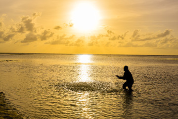 Fototapeta na wymiar Man silhouette on sunrise over the sea ocean waves in Maldives