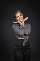 Fototapeta premium Emotional girl in a shirt and black pants posing on dark background.