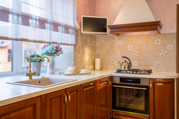 light wooden kitchen set, sink near window  and flower in vase