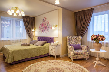 luxurious bedroom in purple and gold colors and rest zone with armchair near window