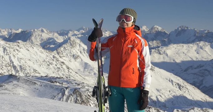 Woman holding skis high in mountains