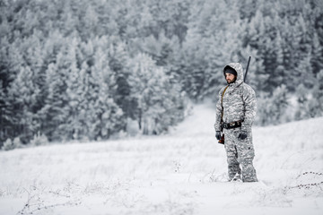 Fototapeta na wymiar Male hunter in camouflage looking for his target or prey .Winter scene