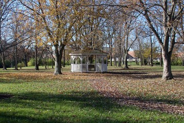 The white gazebo under the autumn trees of the park.