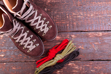 Brown man suede boots and shoelaces on wooden background. Flat lay. Autumn or winter shoes.