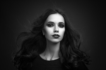 Portrait of the beautiful young woman with long brown hair posing at studio