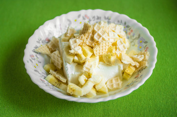 Vanilla ice cream in a plate with pieces of waffle