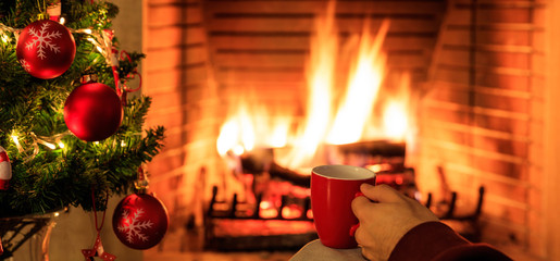 Cup of coffee on Christmas tree and burning fireplace background