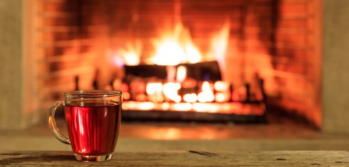 Cup of tea on a burning fireplace background