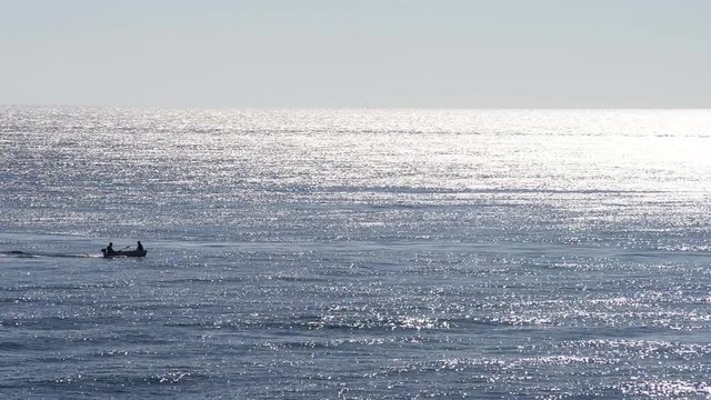 Pescatore sulla sua barca mentre pesca sul mare calmo e pieno ri riflessi