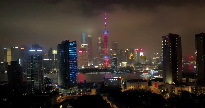 SHANGHAI, CHINA – JUNE 2016 : Aerial shot over Central Shanghai at night with view of Huangpu River, Shanghai Tower, Oriental Pearl TV Tower, Jin Mao Tower and World Financial Center