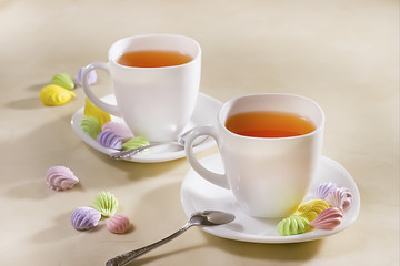 two white cups of tea with colorful meringue