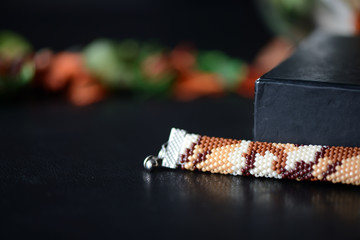 Camouflage bracelet made of seed beads on a dark background close up