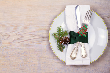 Christmas set with plate, cutlery, pine branches, cinnamon and red berries on wooden place. Winter holidays and festive background. Christmas eve dinner, New Year food lunch. View from above, top