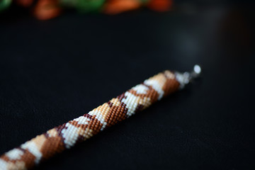 Camouflage bracelet made of seed beads on a dark background close up